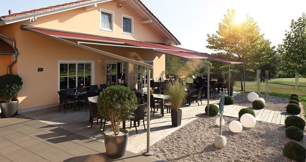 Ein Gestell mit mehreren roten Pergola Markisen von WAREMA über einer großen Terrasse.
