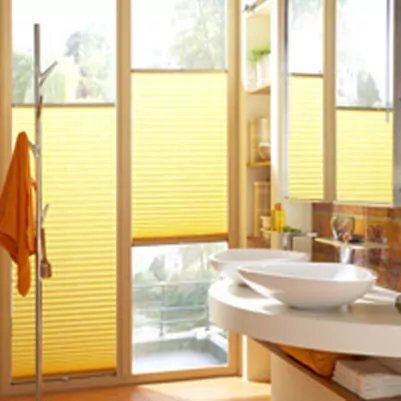 Gelbe Faltstores dimmen das Licht in einem Badezimmer.