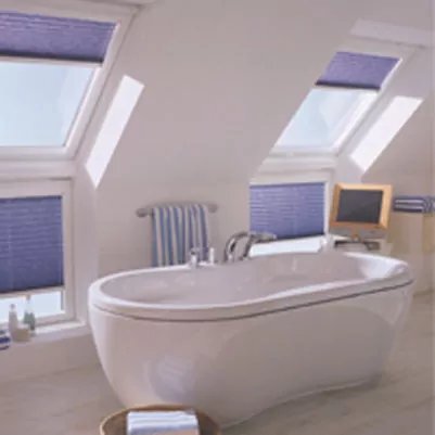 Blaue Plissees an Dachfenstern in einem Badezimmer.