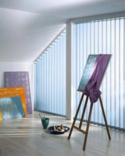 Hellblaue Vertikaljalousien kreieren ein besonderes Licht in einem Atelierraum.