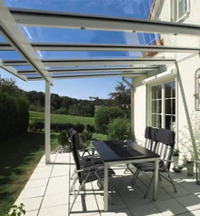 Terrassenvordach aus Glas über Outdoor-Sitzbereich.