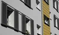 Dunkelgraue Schiebeläden an einer weißen Hausfassade sorgen für eine moderne Stilistik.