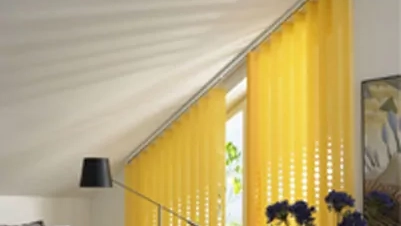 Gelbe Vertikaljalousien an einem Fenster mit Dachschräge verleihen dem Raum Farbe.